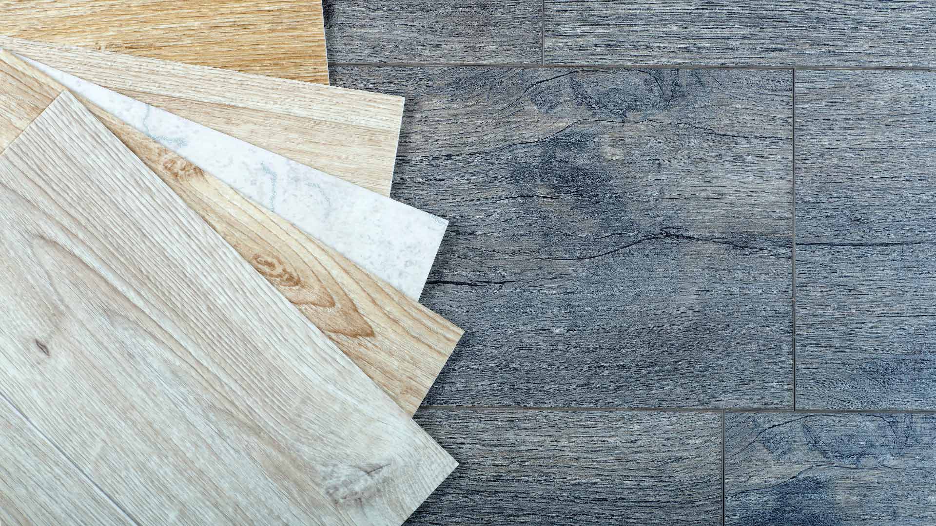Verschiedene Holzfußbodenmuster, farbreich, auf dunklem Holzboden ausgebreitet.
